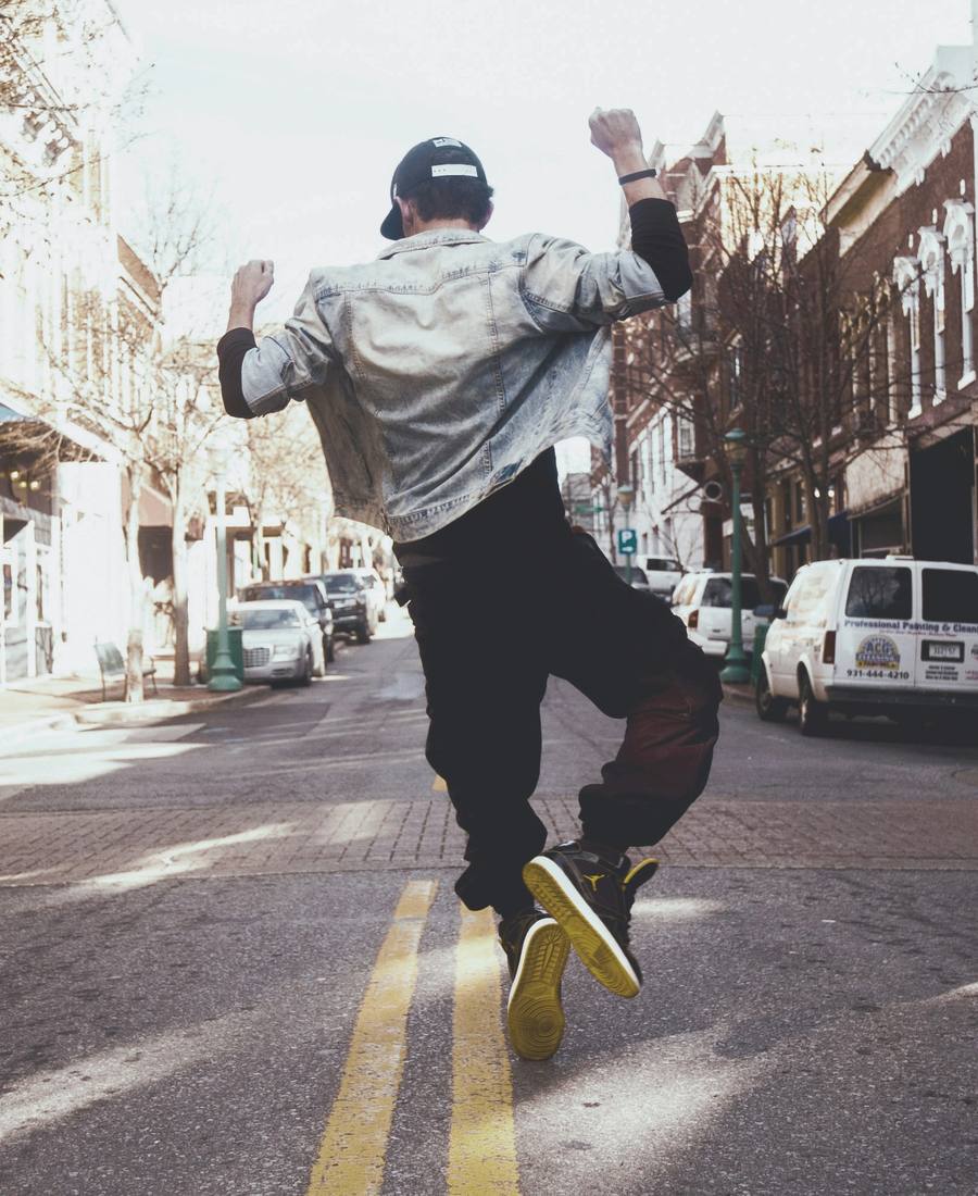 A young man jumping for joy in the middle of a downtown street